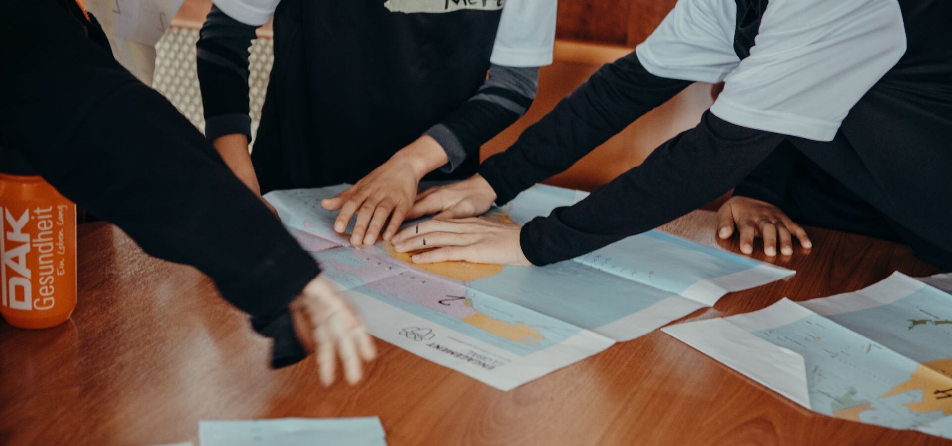 Young people from a football club point to a world map.