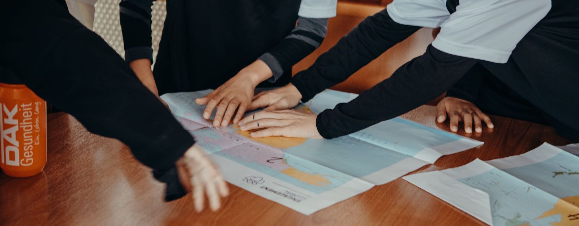 Young people from a football club point to a world map.